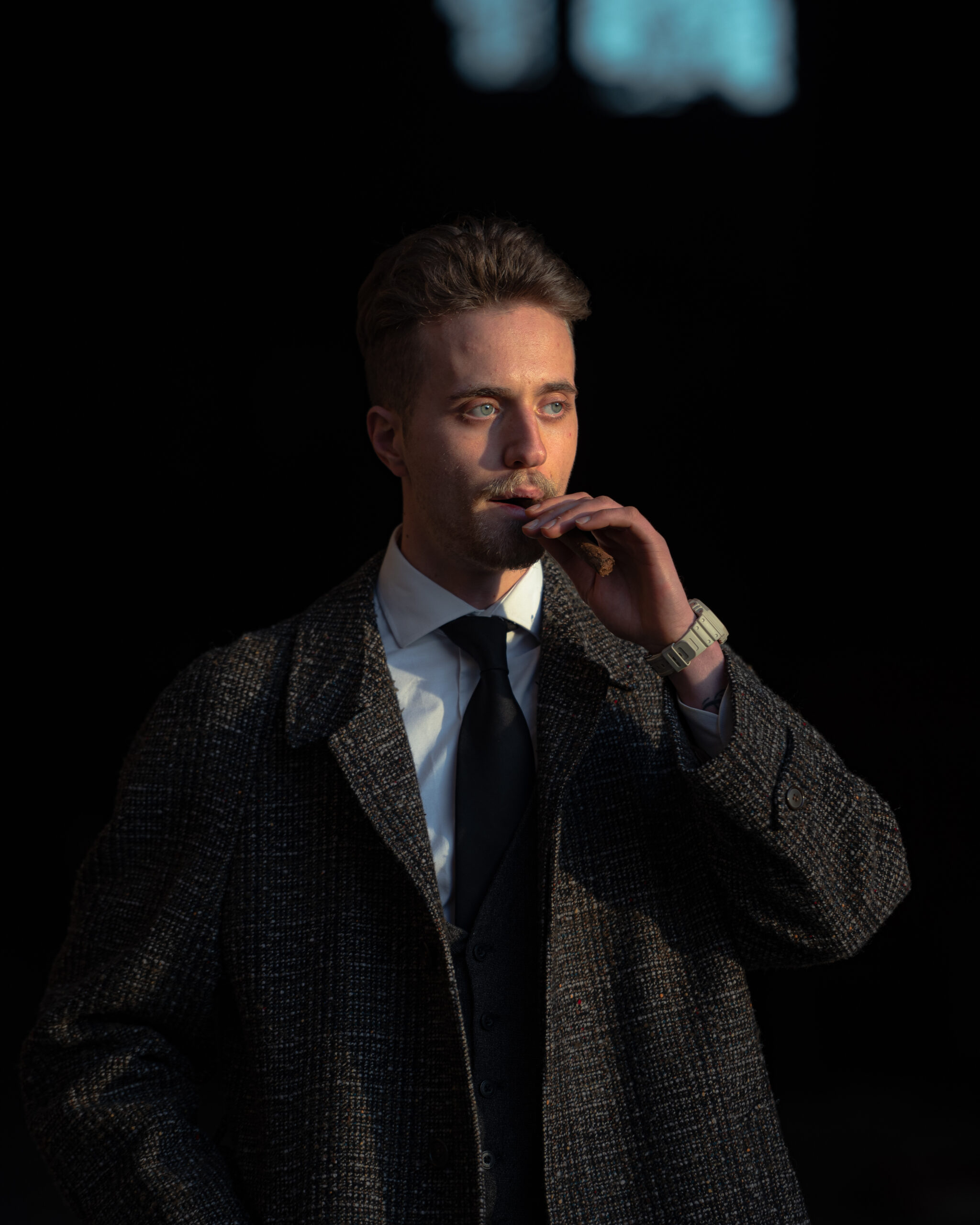 Man in elegant coat and tie enjoying a cigar. Chic and fashionable look.