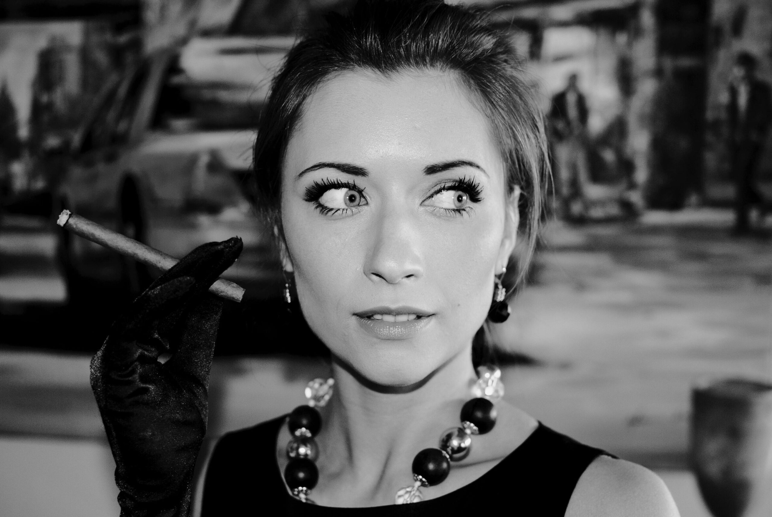 Elegant black and white portrait of a woman with a cigar and stylish necklace.