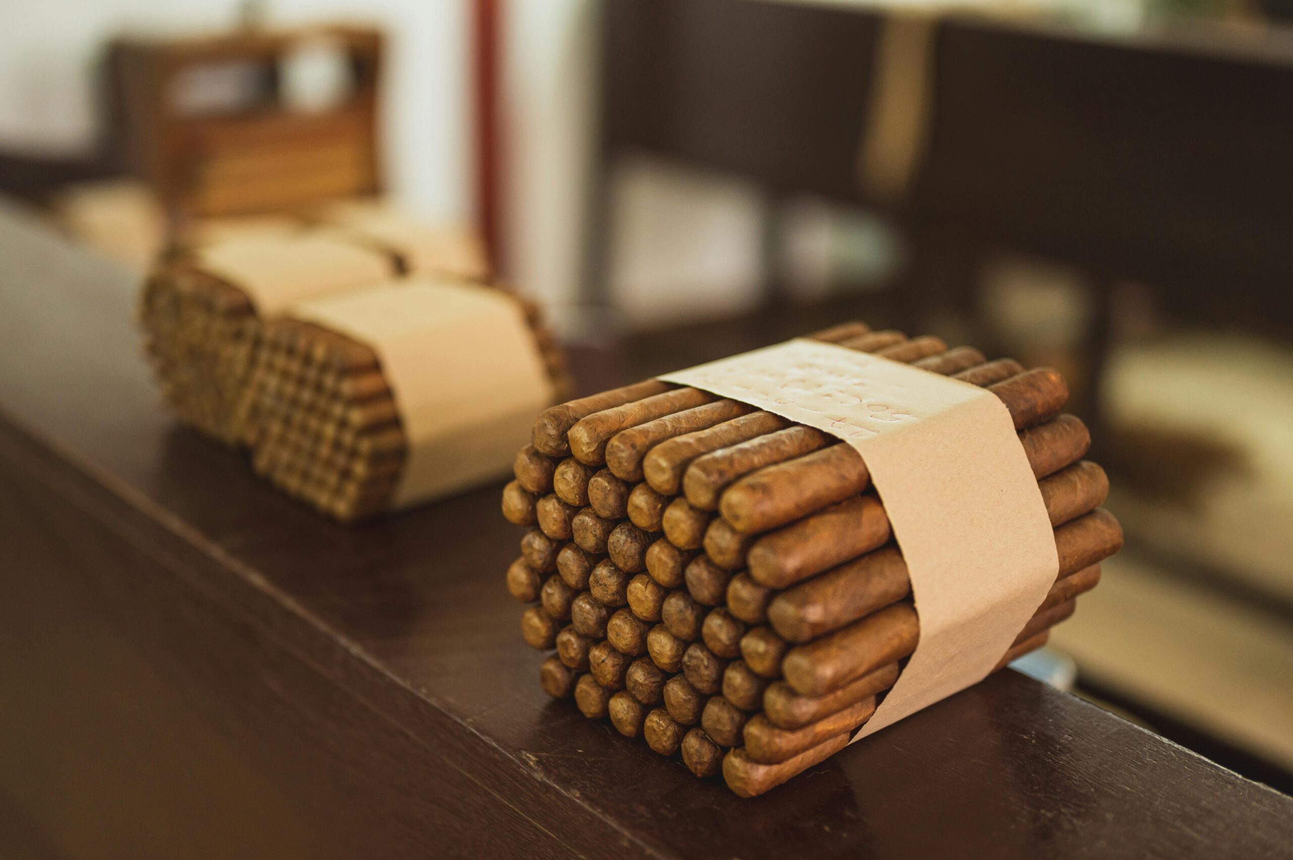 From above of piles of uncooked packed cigars with rounded edges put in row on wooden surface in factory on blurred background
